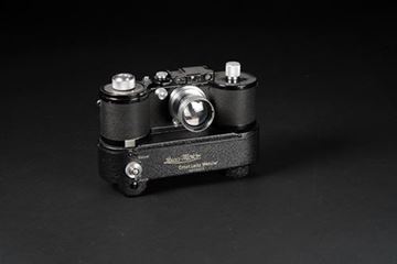 Picture of Leica 250 Reporter (Model GG) SN 353 672; Summitar 2/50 SN 585 937; Electric Motor SN 10063; with both mechanical and electrical winding devices (c.1940s). The first electrical motor drive for a Leica camera was  the MOOEV for Leica 250 Reporter of 1941. About 100 of these motor drives were completed and delivered to the German and Italian air forces during World War II.